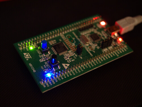 Photo of STM32 discovery board with illuminated green and blue LEDs